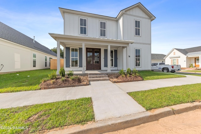 modern inspired farmhouse with a front lawn, a porch, and board and batten siding