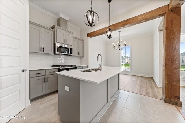 kitchen with gray cabinetry, stainless steel appliances, a sink, decorative backsplash, and crown molding