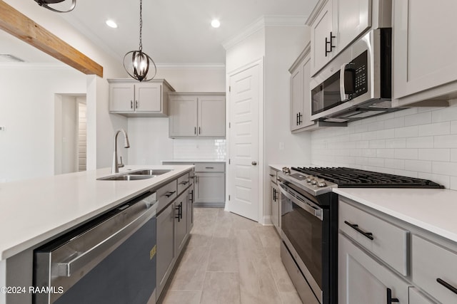 kitchen featuring crown molding, gray cabinets, light countertops, appliances with stainless steel finishes, and a sink