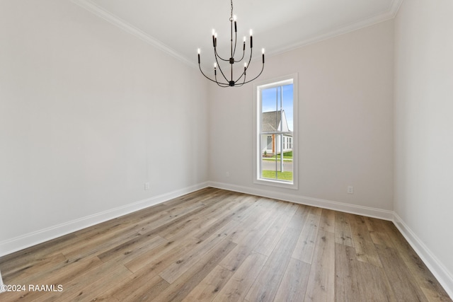 spare room featuring light wood-style floors, baseboards, ornamental molding, and a notable chandelier