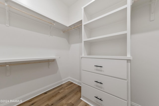 walk in closet with wood finished floors