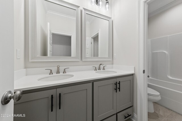 bathroom featuring double vanity, ornamental molding, toilet, and a sink