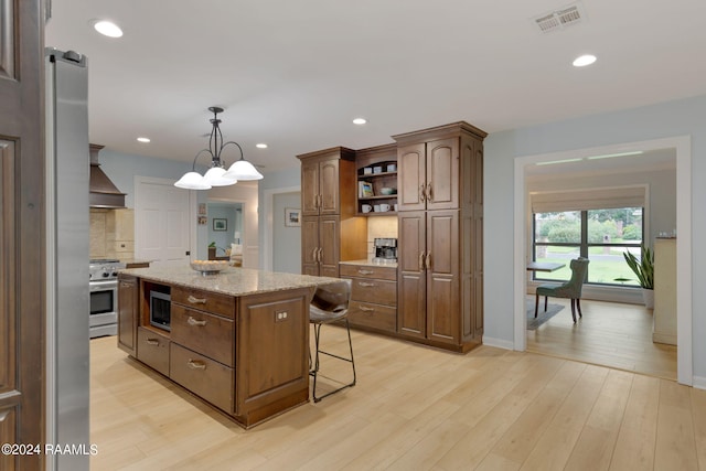 kitchen featuring custom exhaust hood, light hardwood / wood-style flooring, a center island, appliances with stainless steel finishes, and a barn door