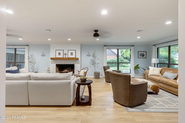 living room with a brick fireplace, light hardwood / wood-style flooring, and ceiling fan