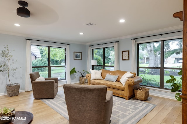 living area featuring crown molding, light wood-style flooring, baseboards, and visible vents