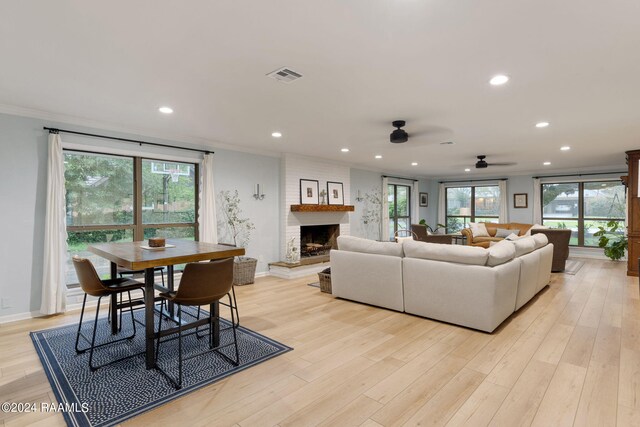 living room featuring a fireplace, plenty of natural light, ceiling fan, and light hardwood / wood-style floors