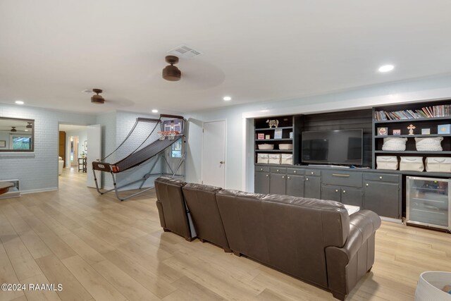 living room featuring brick wall, wine cooler, and light hardwood / wood-style floors