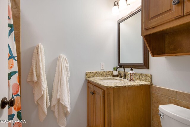 bathroom with vanity, toilet, walk in shower, and tile walls