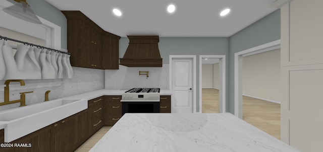 kitchen featuring custom range hood, dark brown cabinetry, backsplash, and light hardwood / wood-style floors