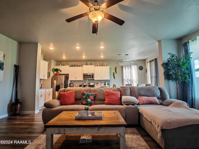 living room with ceiling fan with notable chandelier and dark hardwood / wood-style floors