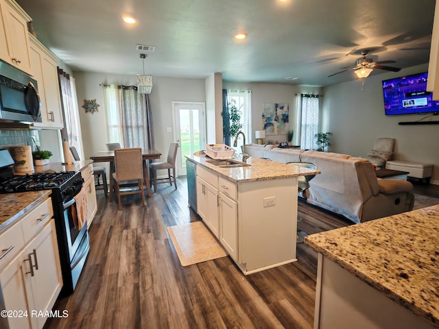 kitchen featuring white cabinets, an island with sink, hanging light fixtures, dark wood-type flooring, and stainless steel appliances