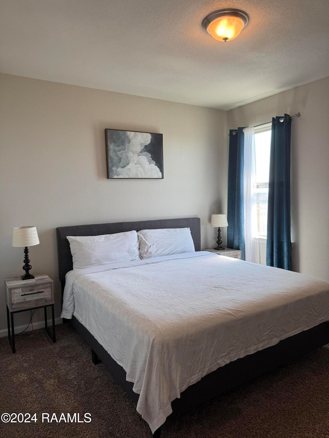 bedroom featuring a textured ceiling and dark colored carpet