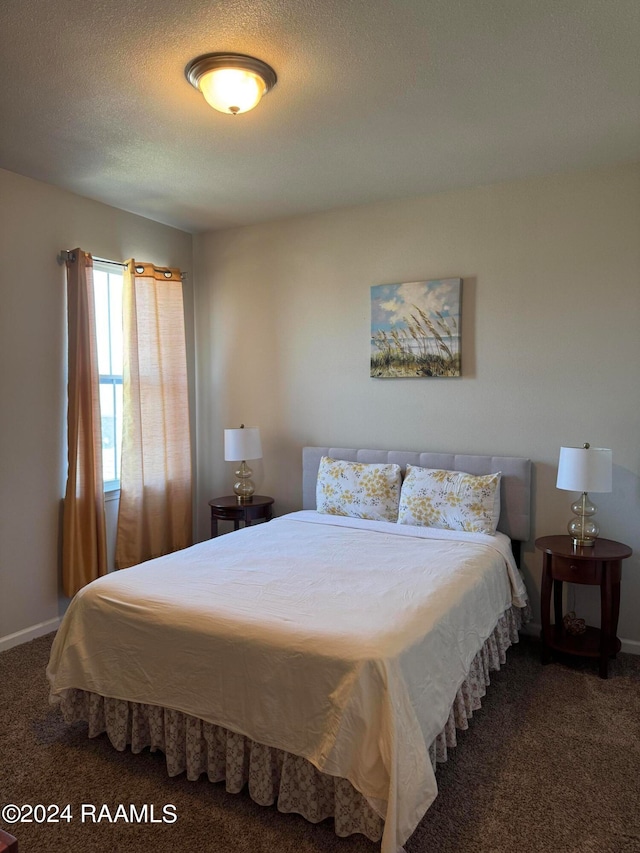 bedroom with a textured ceiling and dark colored carpet