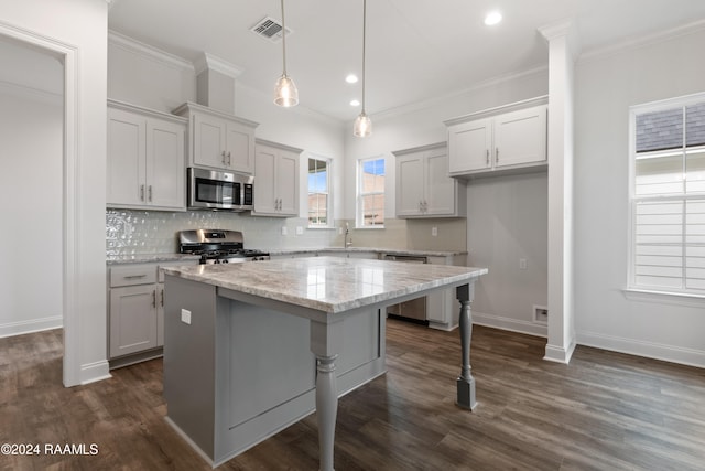 kitchen featuring ornamental molding, stainless steel appliances, dark hardwood / wood-style flooring, light stone countertops, and a center island