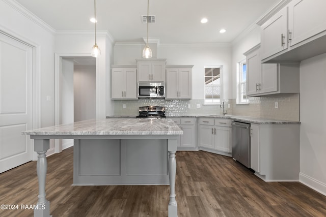 kitchen with crown molding, appliances with stainless steel finishes, dark wood-type flooring, and decorative light fixtures