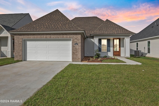 view of front of house with a lawn, a garage, and cooling unit