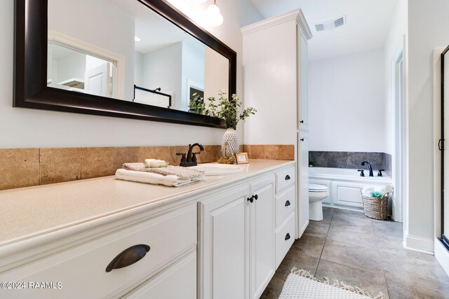 bathroom featuring vanity, a tub to relax in, tile patterned floors, and toilet