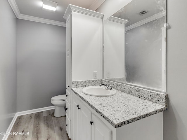 bathroom featuring wood-type flooring, toilet, ornamental molding, and vanity