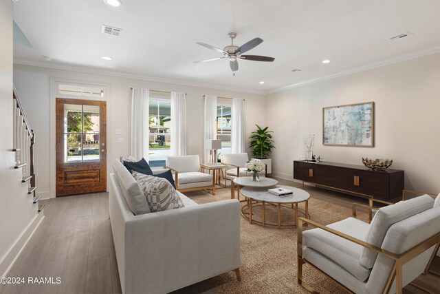 living room with ceiling fan, light wood-type flooring, ornamental molding, and a wealth of natural light