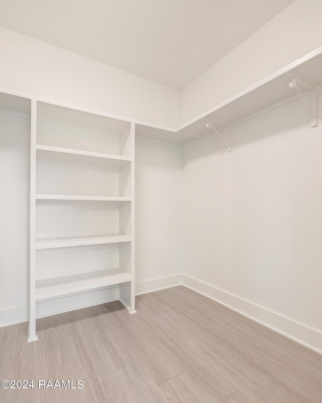 walk in closet with light hardwood / wood-style flooring