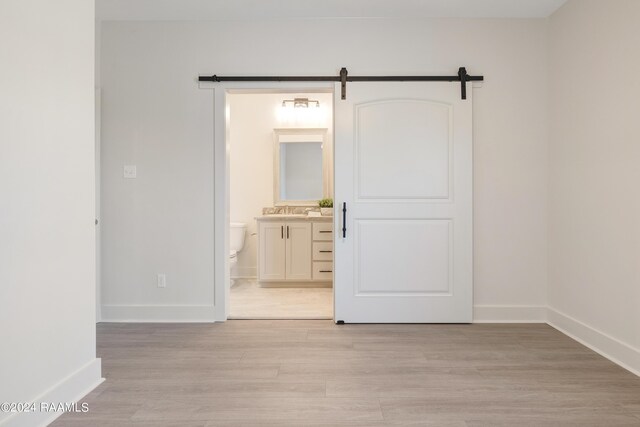 unfurnished room featuring light wood-type flooring and a barn door