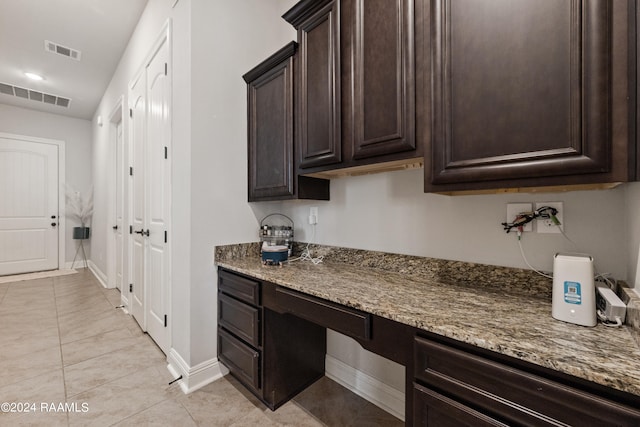 kitchen with stone countertops, light tile patterned floors, and dark brown cabinetry