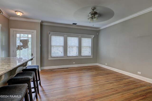 unfurnished dining area with ceiling fan, ornamental molding, and light hardwood / wood-style floors