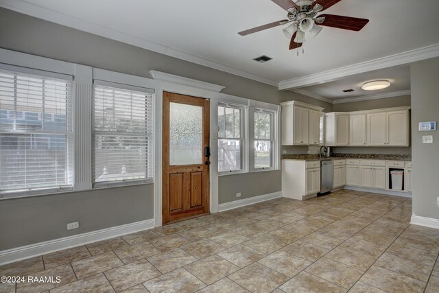 kitchen with light tile patterned floors, ceiling fan, white cabinetry, ornamental molding, and stainless steel dishwasher