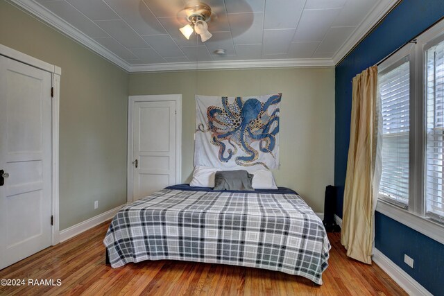 bedroom with hardwood / wood-style flooring, ceiling fan, crown molding, and multiple windows