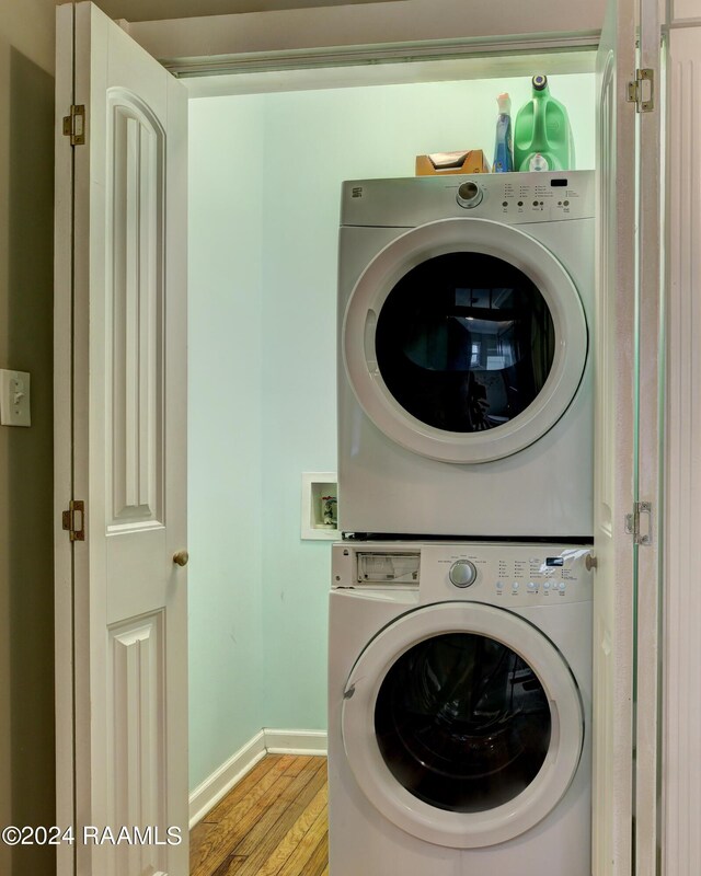 laundry area featuring stacked washer and clothes dryer and light wood-type flooring