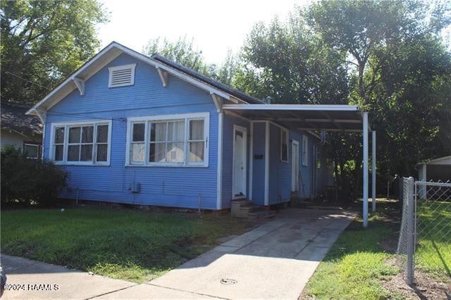 bungalow-style house with a front lawn and a carport