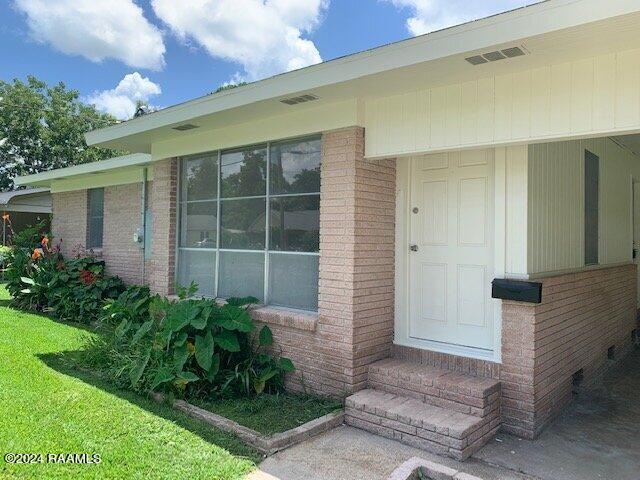 doorway to property featuring a lawn