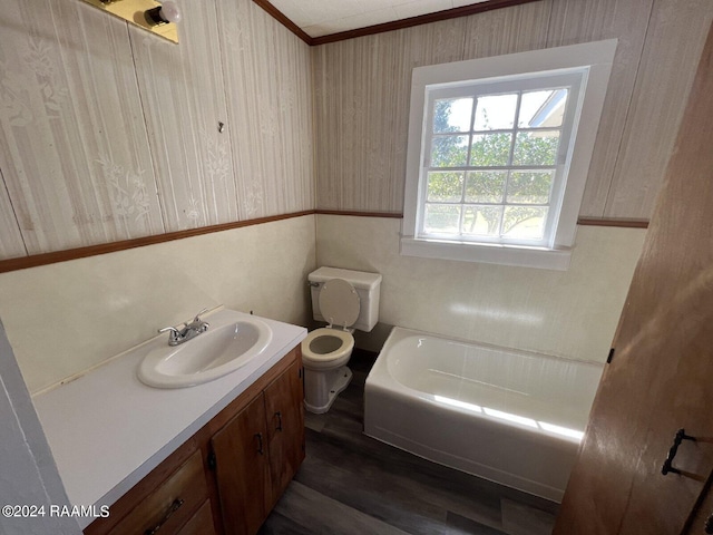 bathroom featuring a bathing tub, hardwood / wood-style floors, vanity, ornamental molding, and toilet