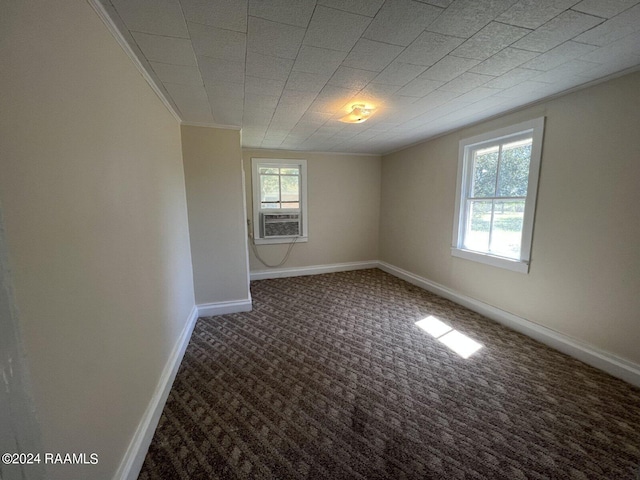 unfurnished room featuring cooling unit, dark carpet, and crown molding