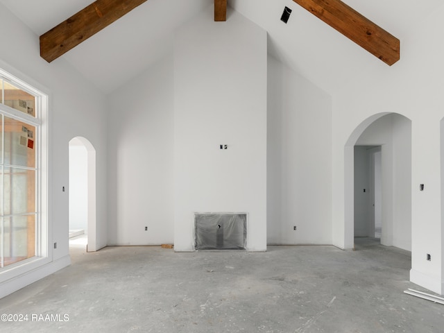 unfurnished living room with a healthy amount of sunlight, beamed ceiling, and high vaulted ceiling