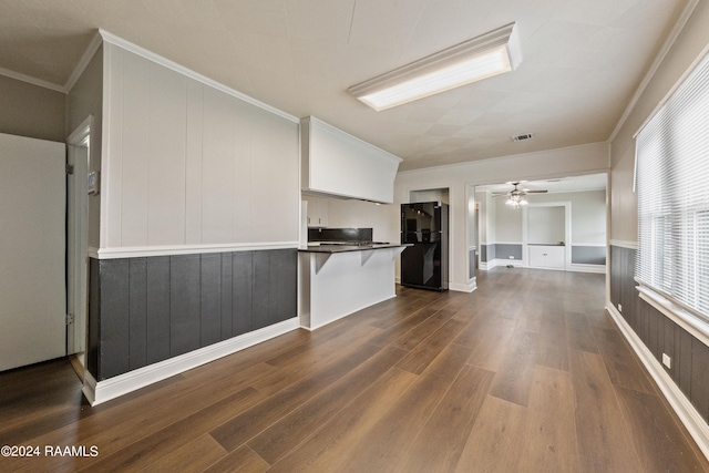 unfurnished living room with ceiling fan, ornamental molding, and dark hardwood / wood-style floors