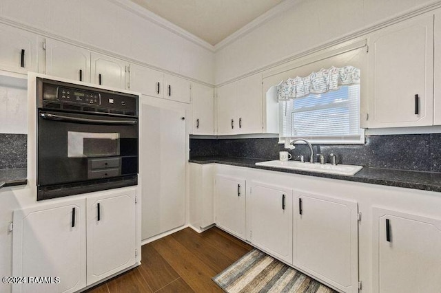 kitchen featuring sink, crown molding, dark wood-type flooring, white cabinets, and oven