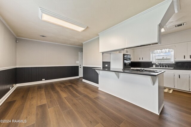 kitchen featuring sink, a breakfast bar, white cabinetry, stainless steel gas cooktop, and dark hardwood / wood-style flooring