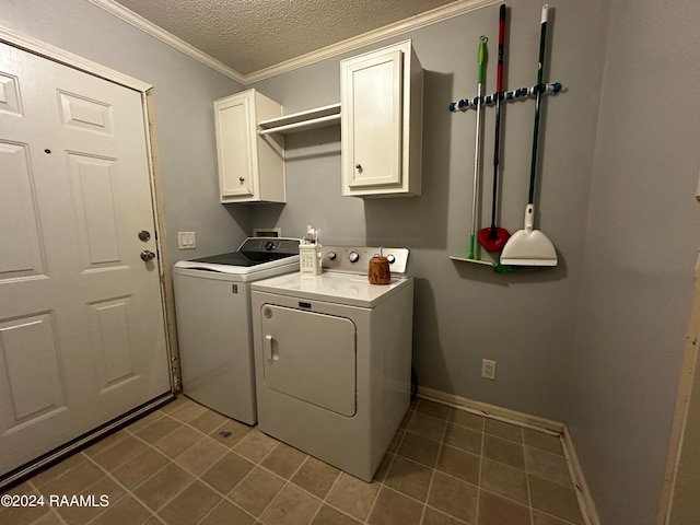 washroom with dark tile patterned floors, ornamental molding, washing machine and clothes dryer, cabinets, and a textured ceiling