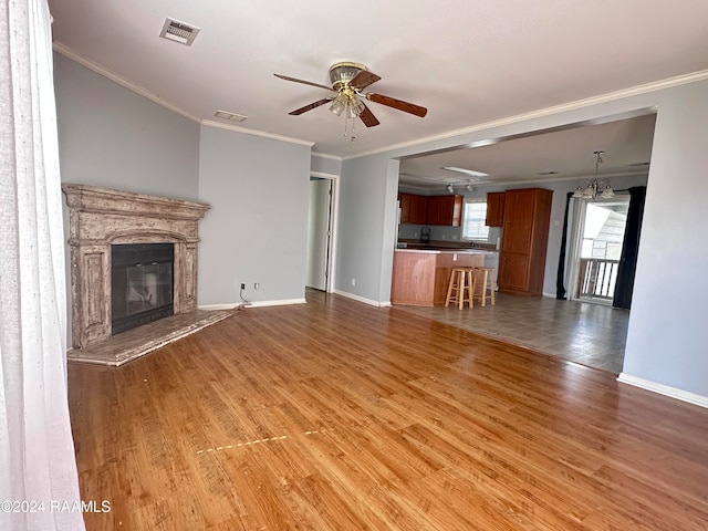 unfurnished living room featuring ornamental molding, hardwood / wood-style flooring, and ceiling fan with notable chandelier