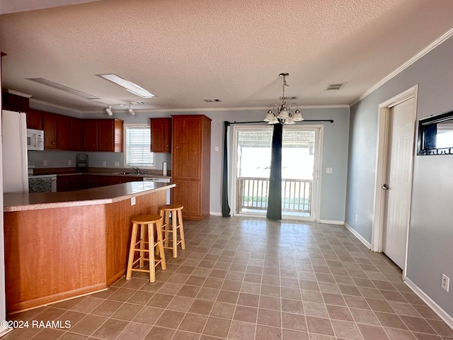 kitchen with ornamental molding, a breakfast bar, a notable chandelier, a textured ceiling, and white appliances