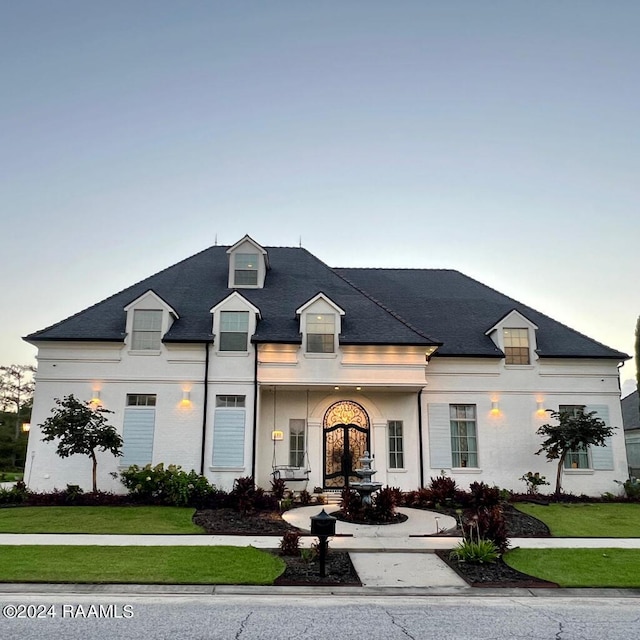 french country inspired facade with a front lawn and stucco siding