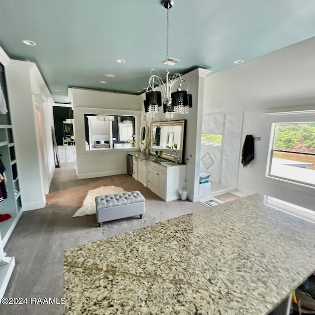 kitchen with pendant lighting, light carpet, white cabinets, and a chandelier