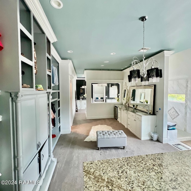 kitchen with hanging light fixtures, light carpet, and white cabinetry