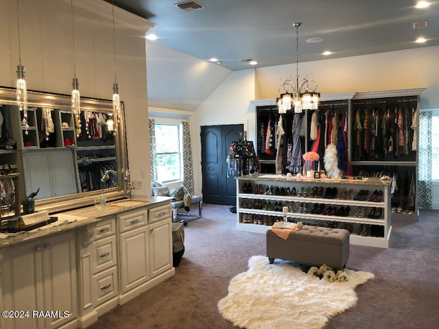 interior space with lofted ceiling, a chandelier, dark colored carpet, light stone countertops, and hanging light fixtures