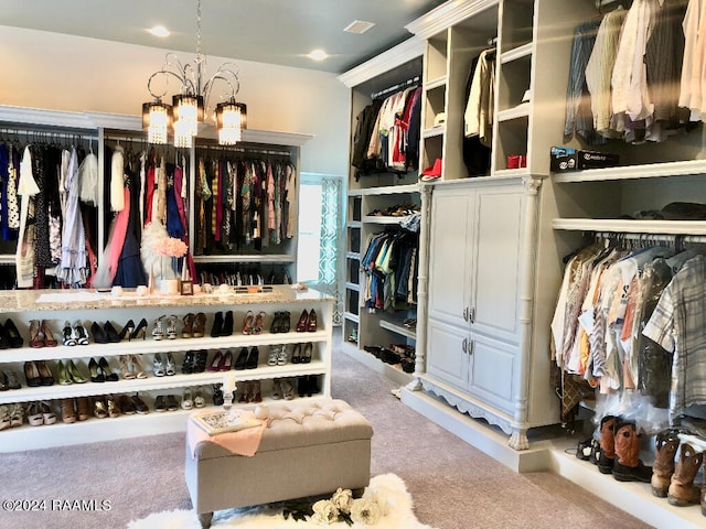 spacious closet with carpet floors and an inviting chandelier