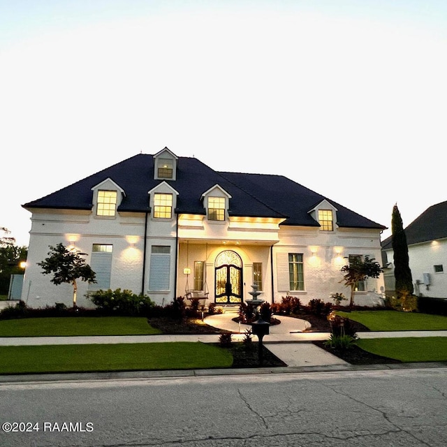 french provincial home featuring a front lawn and stucco siding