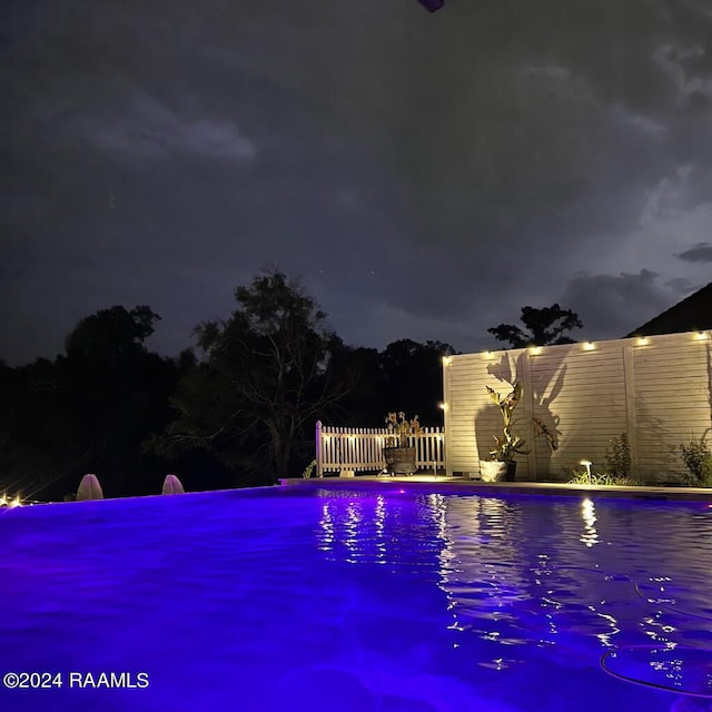 pool at night with fence and an outdoor pool