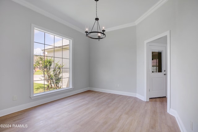 spare room featuring a chandelier, a healthy amount of sunlight, crown molding, and light wood-type flooring