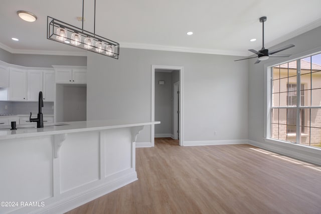 kitchen featuring white cabinetry, tasteful backsplash, crown molding, sink, and light hardwood / wood-style flooring